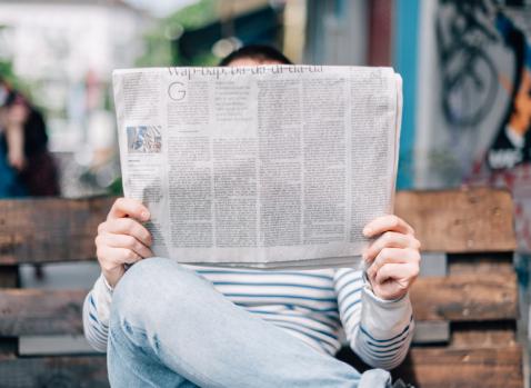 Photographie d'un homme assis lisant un journal