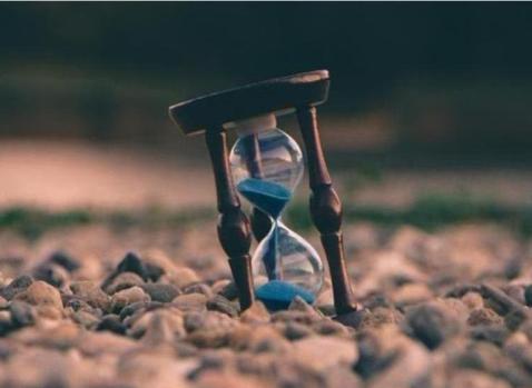 Photographie d'un sablier bleu posé sur le sol