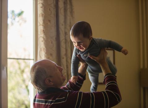 Photographie d'un grand-père tenant dans ses bras son petit-fils